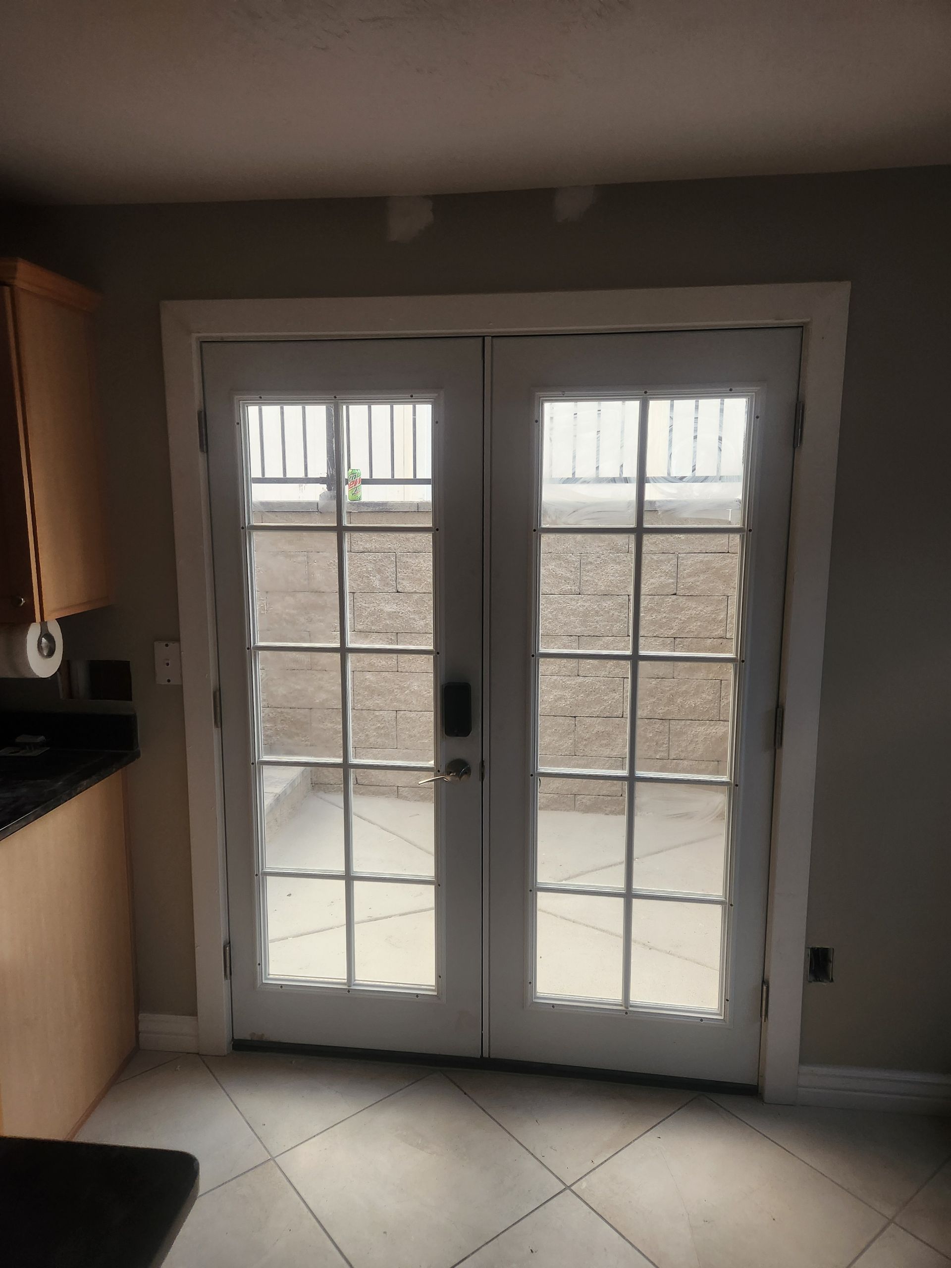 Kitchen with white French doors opening to a small patio and brick wall outside.