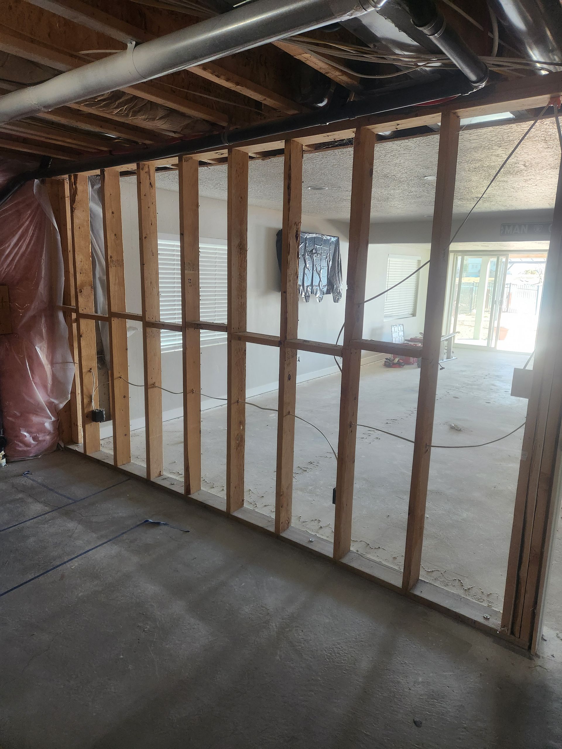 Unfinished room with exposed wall studs, insulation, and concrete floor, viewed through a doorway.