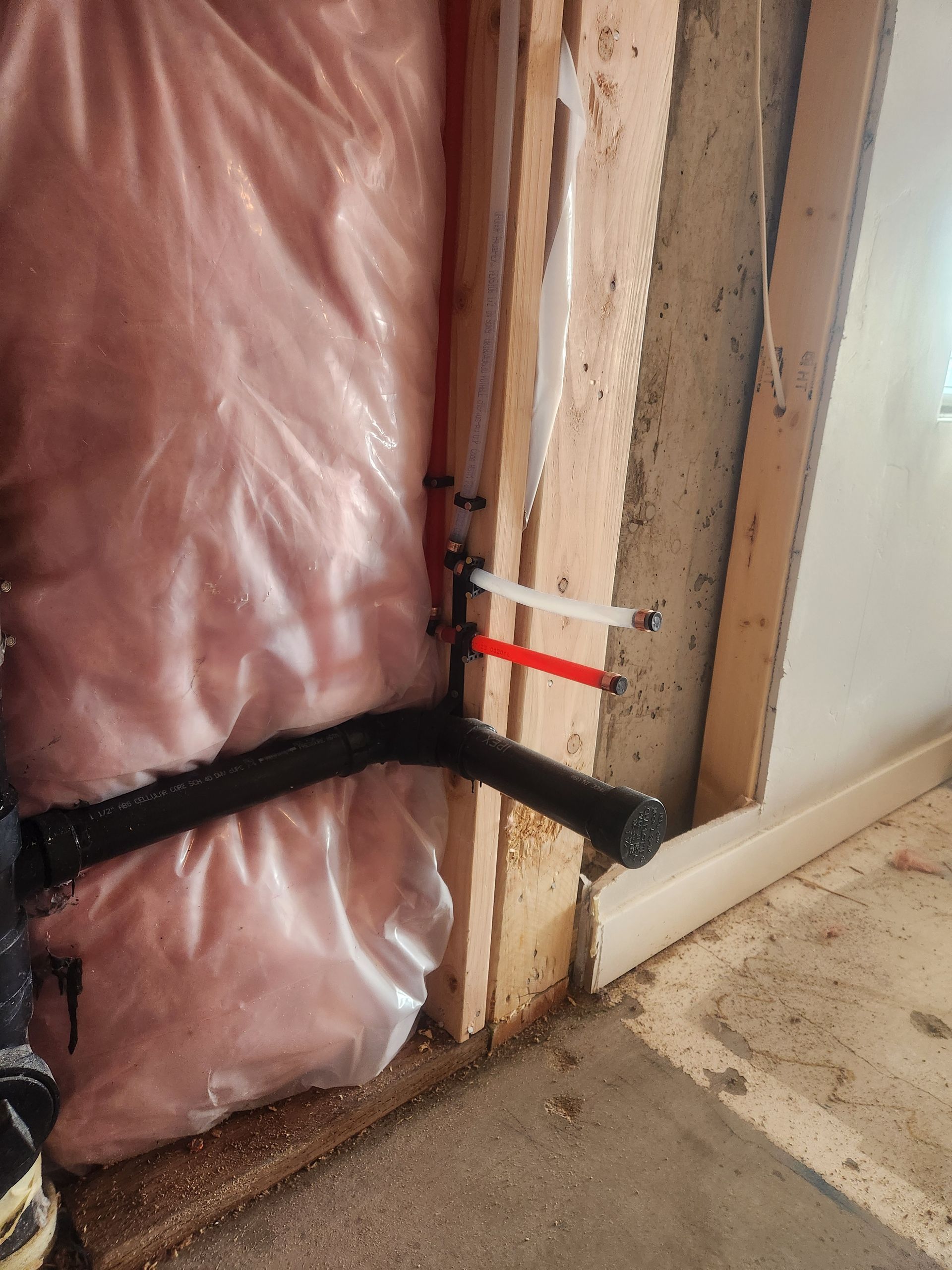 Pink insulation and taped wiring beside a door frame, with black straps across the wall opening.
