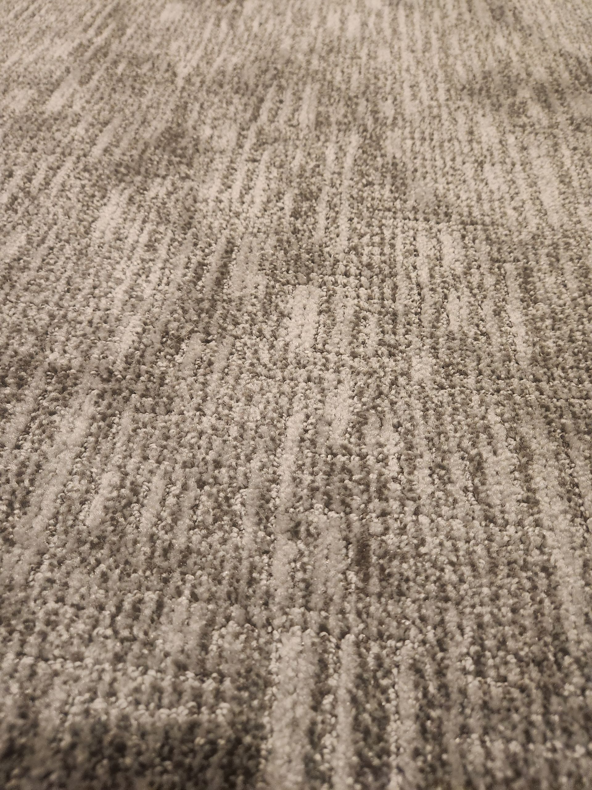 Close-up of a beige and gray textured carpet pattern