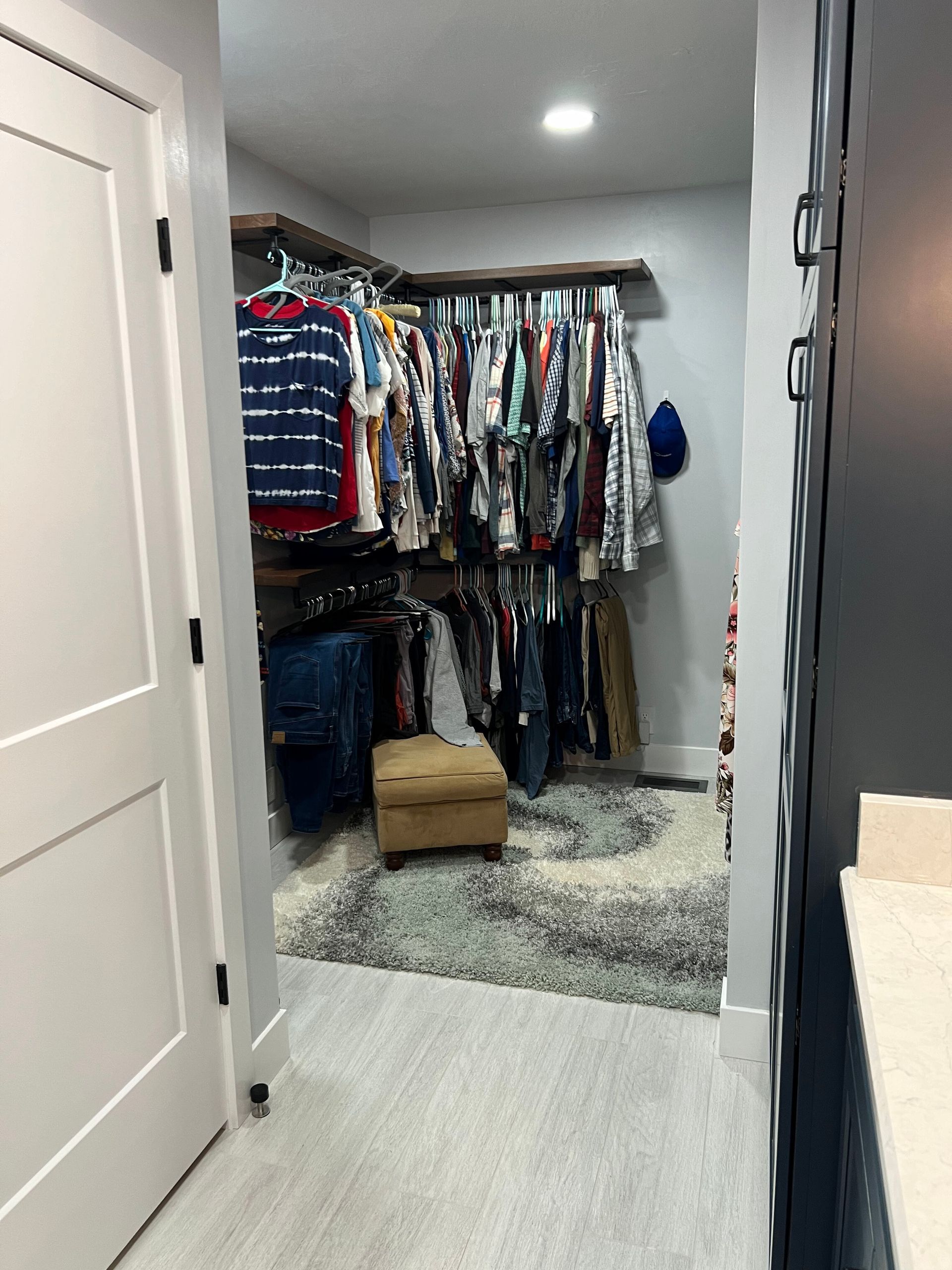 Walk-in closet with hanging clothes, shelves, and a cardboard box on the floor