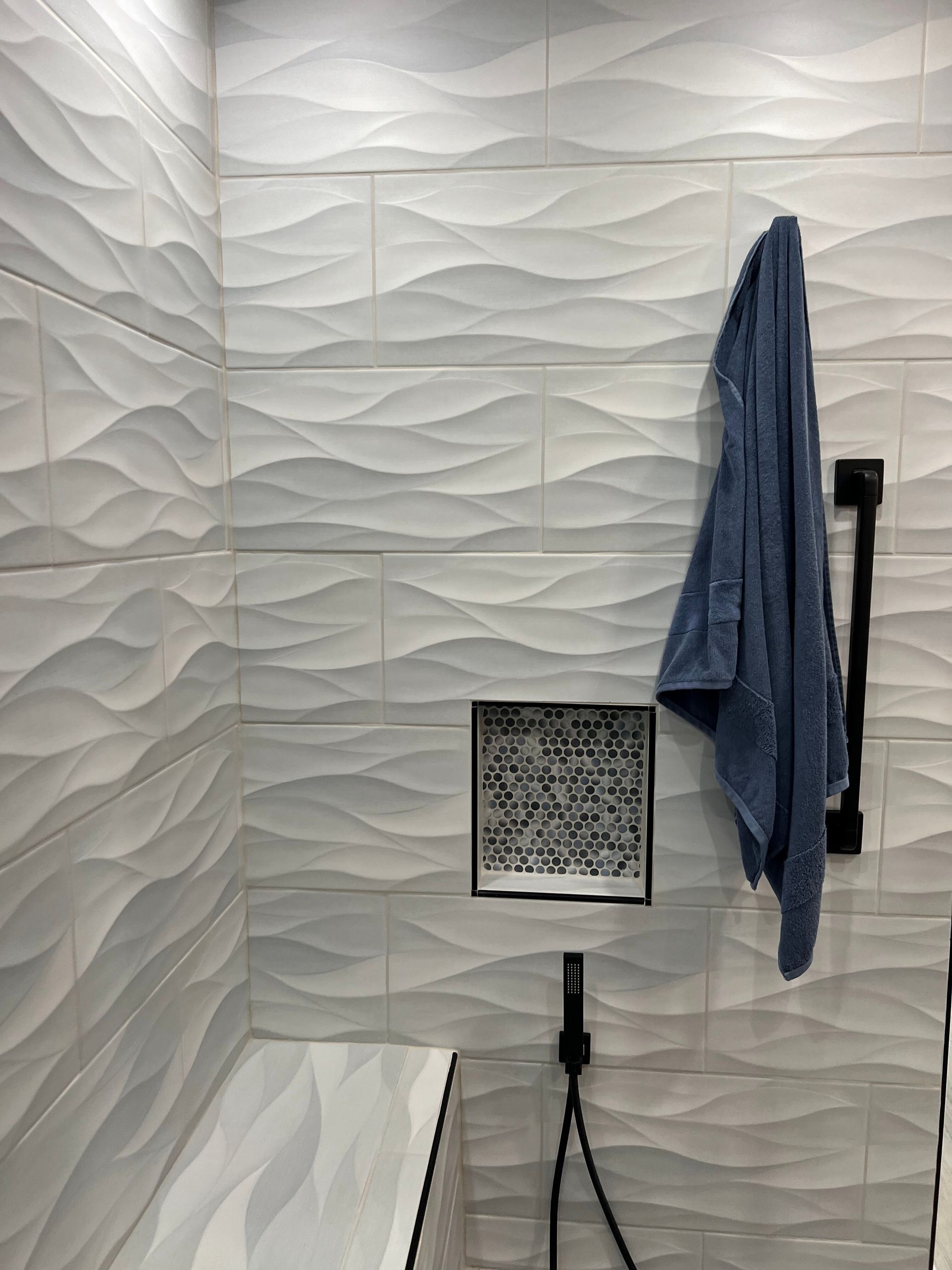 Small square lamp on tripod in a white textured room, with a blue towel hanging on the wall.