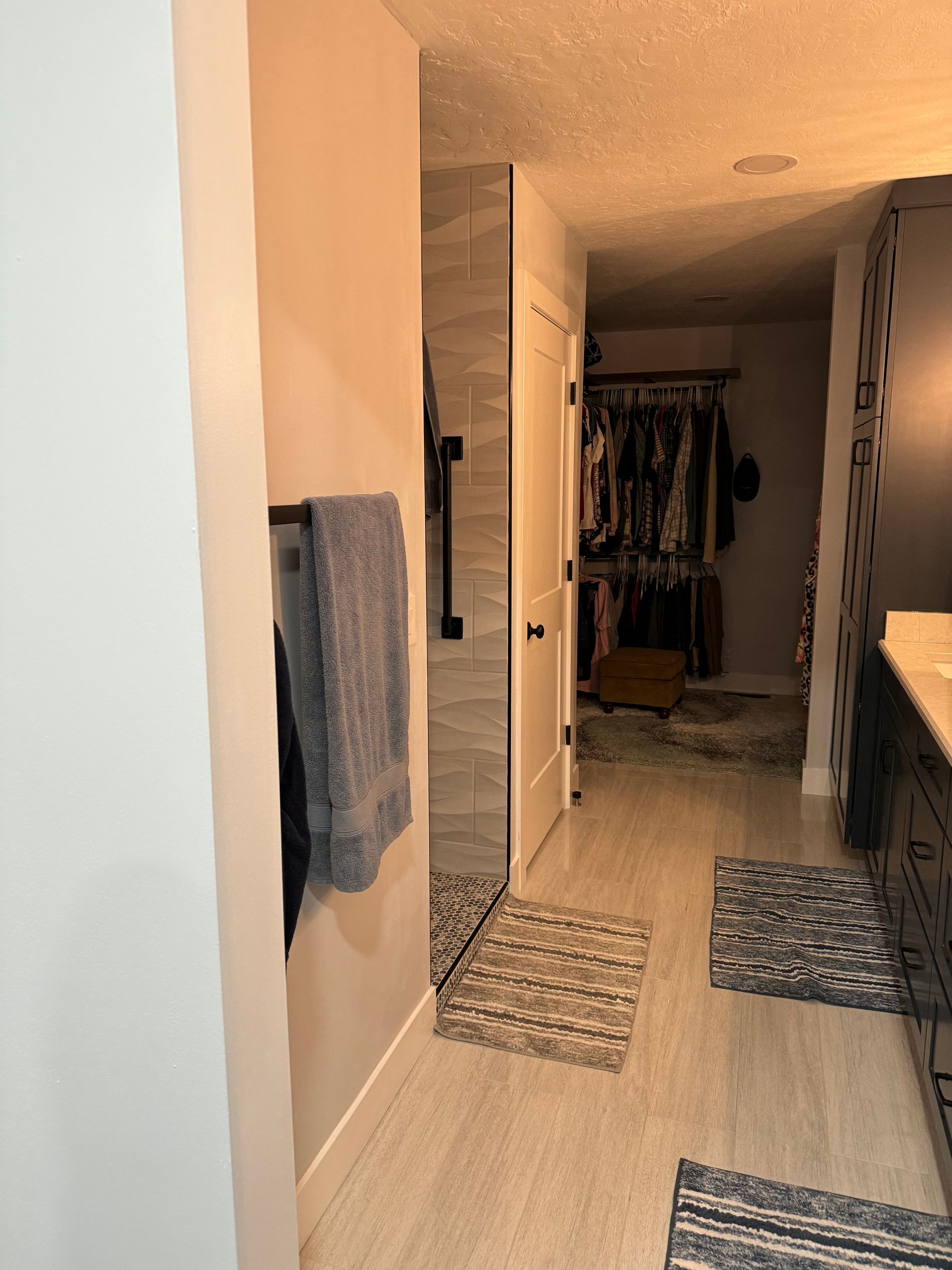 Narrow hallway with rugs, hanging towels, and a closet area at the end.