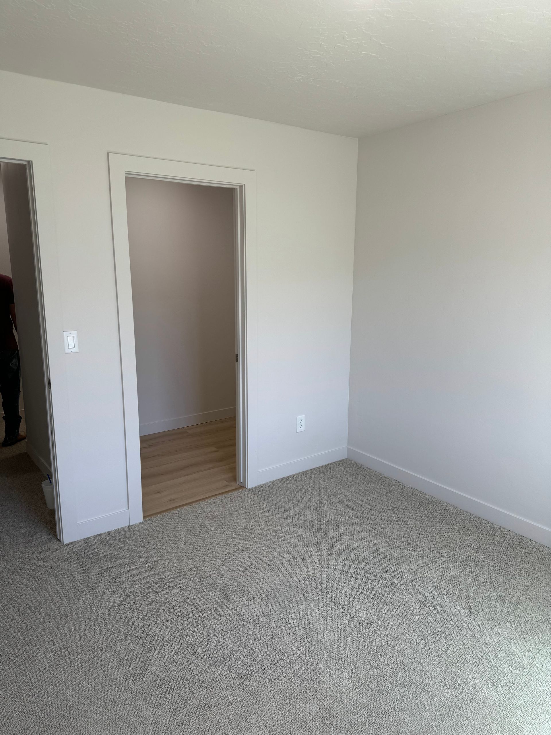 Empty carpeted bedroom with white walls and an open doorway to a hallway