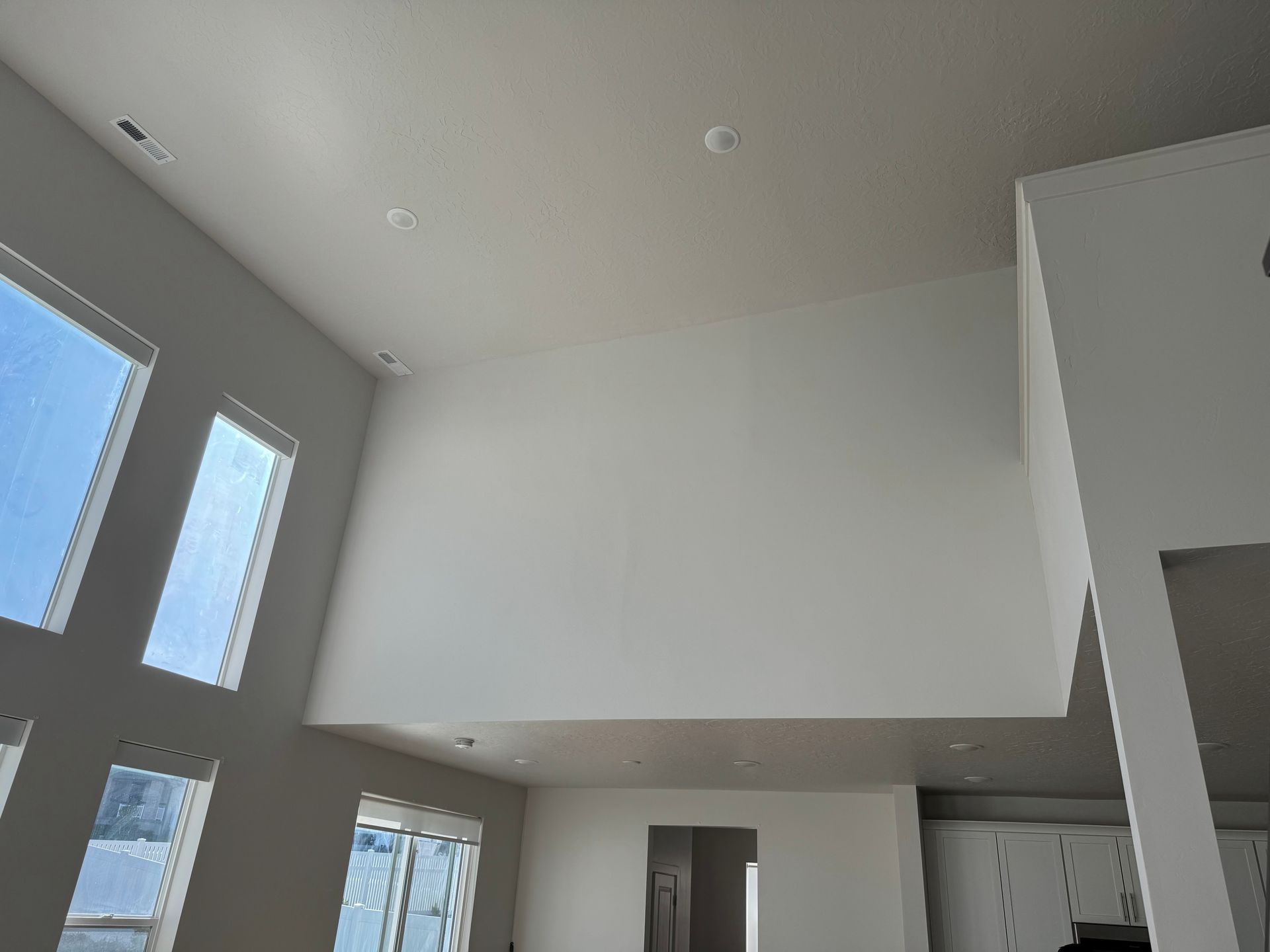 Bright, modern room with high white ceilings, large windows, and an open loft-like mezzanine.