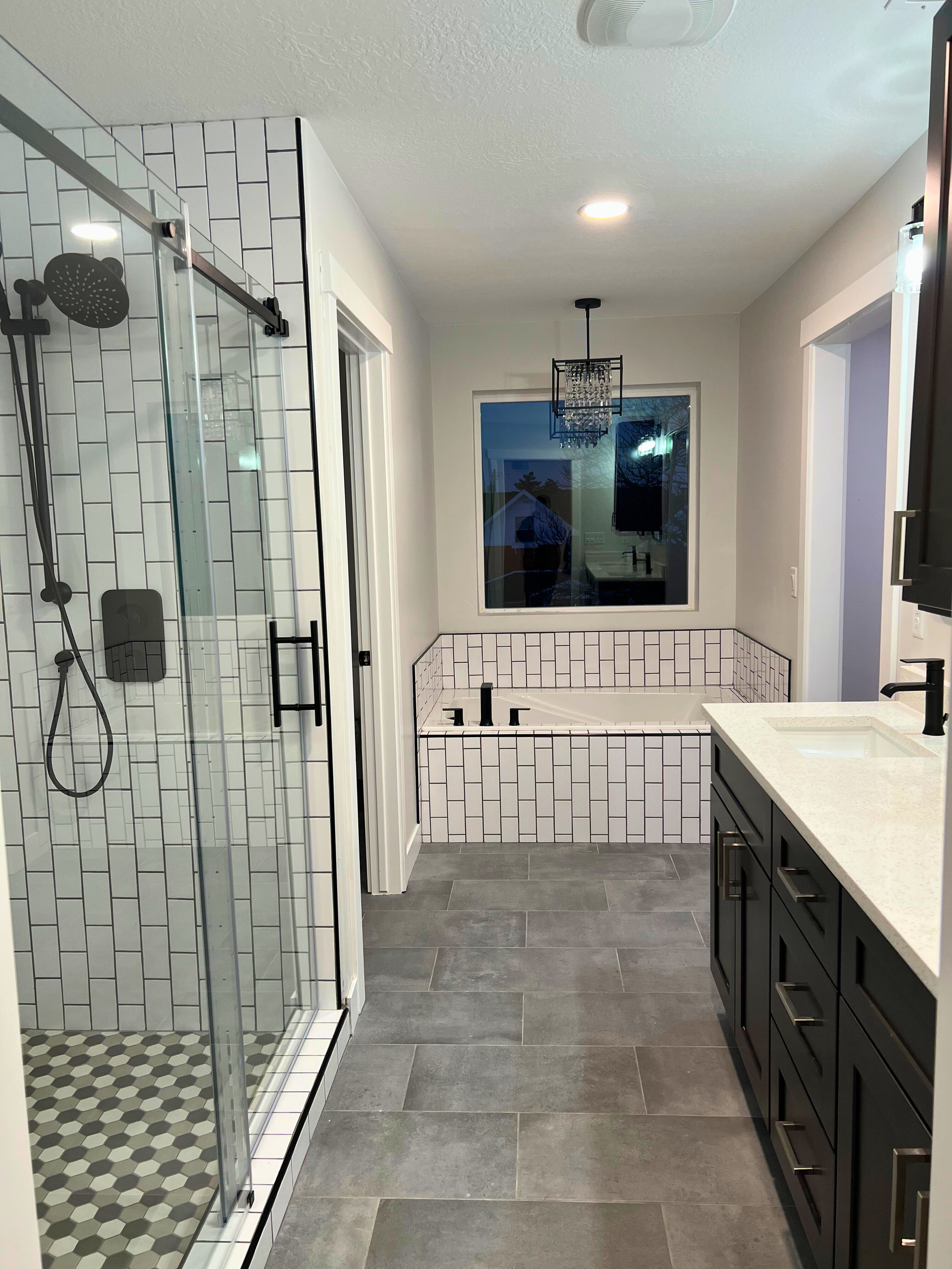 Modern bathroom with glass shower, double vanity, and freestanding tub in a gray and white palette
