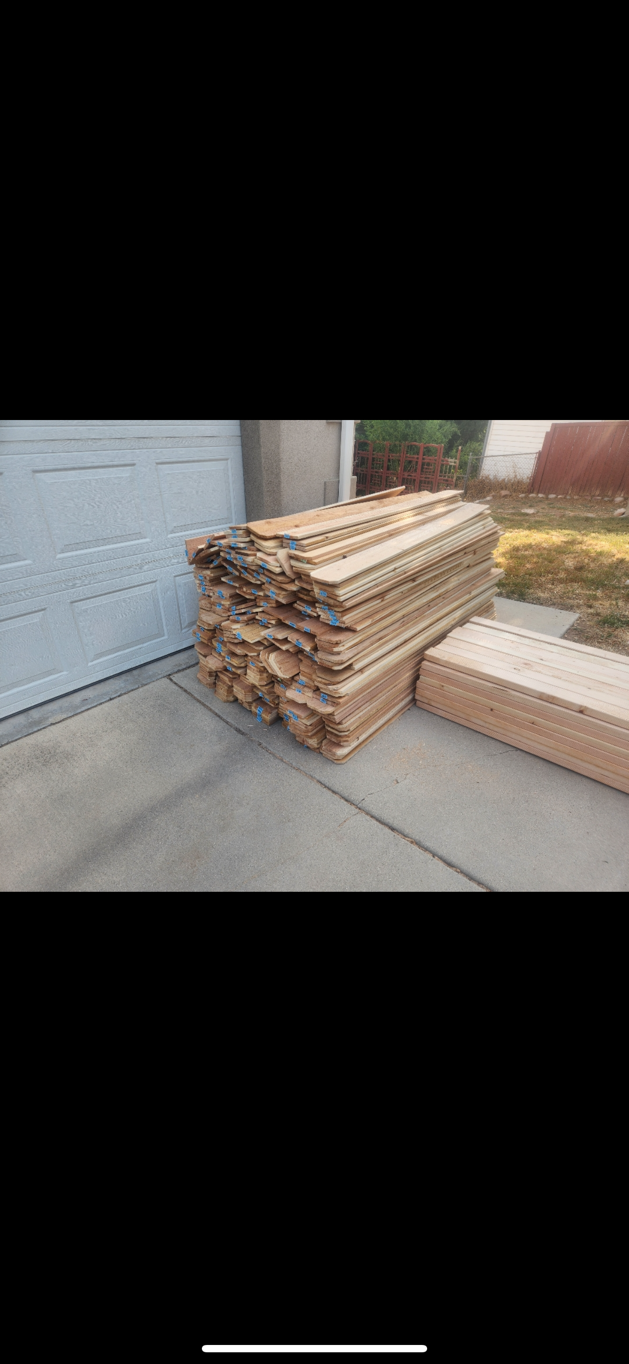 Stacked cardboard boxes and packing material beside a building entrance on a concrete walkway