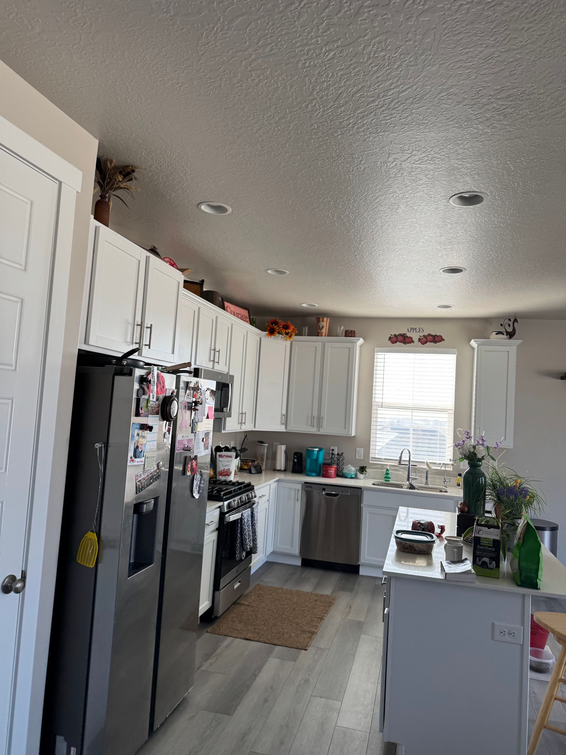 Bright kitchen with white cabinets, black appliances, a window over the sink, and a small island.