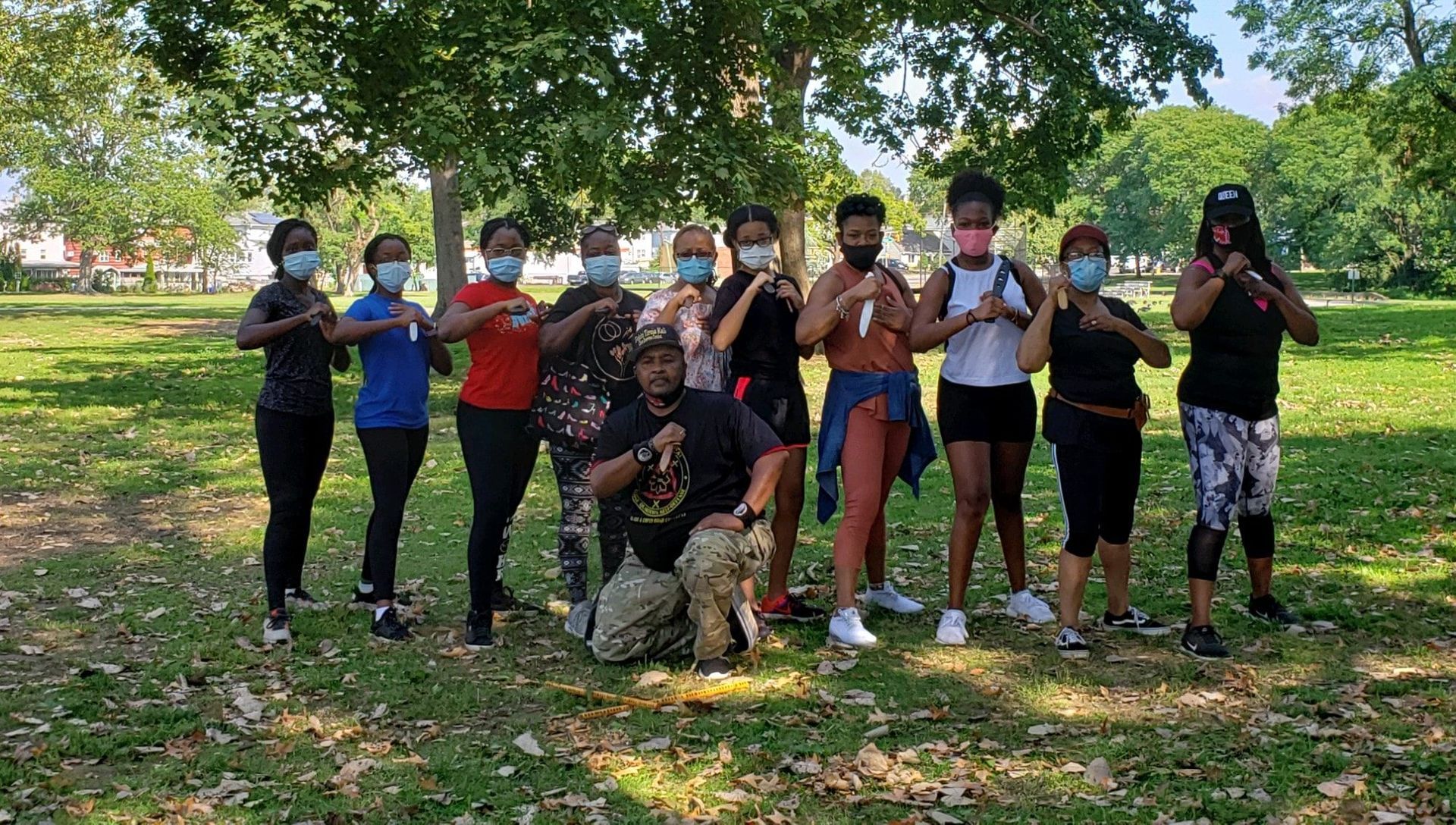 A group of people wearing face masks are posing for a picture in a park.