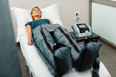 Paziente sdraiato su un lettino da trattamento in una clinica, all'interno di un dispositivo per la terapia a compressione d'aria.