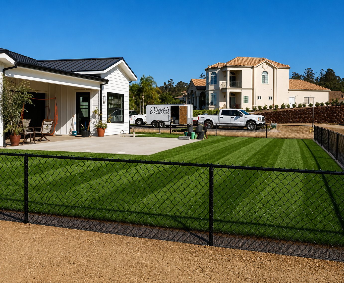 Suburban house with manicured lawn, black fence, and parked white truck under a clear blue sky