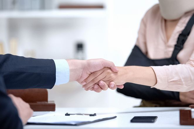 A woman in a cast is shaking hands with a man in a suit.