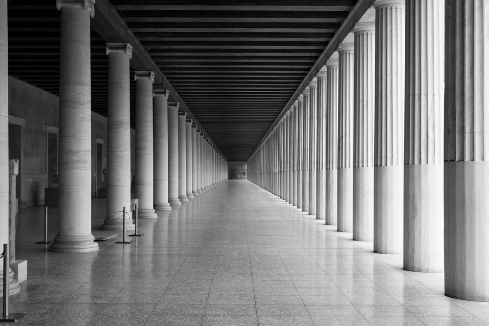 A black and white photo of a long hallway with columns.
