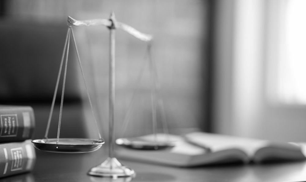 A scale of justice is sitting on a table next to a book.