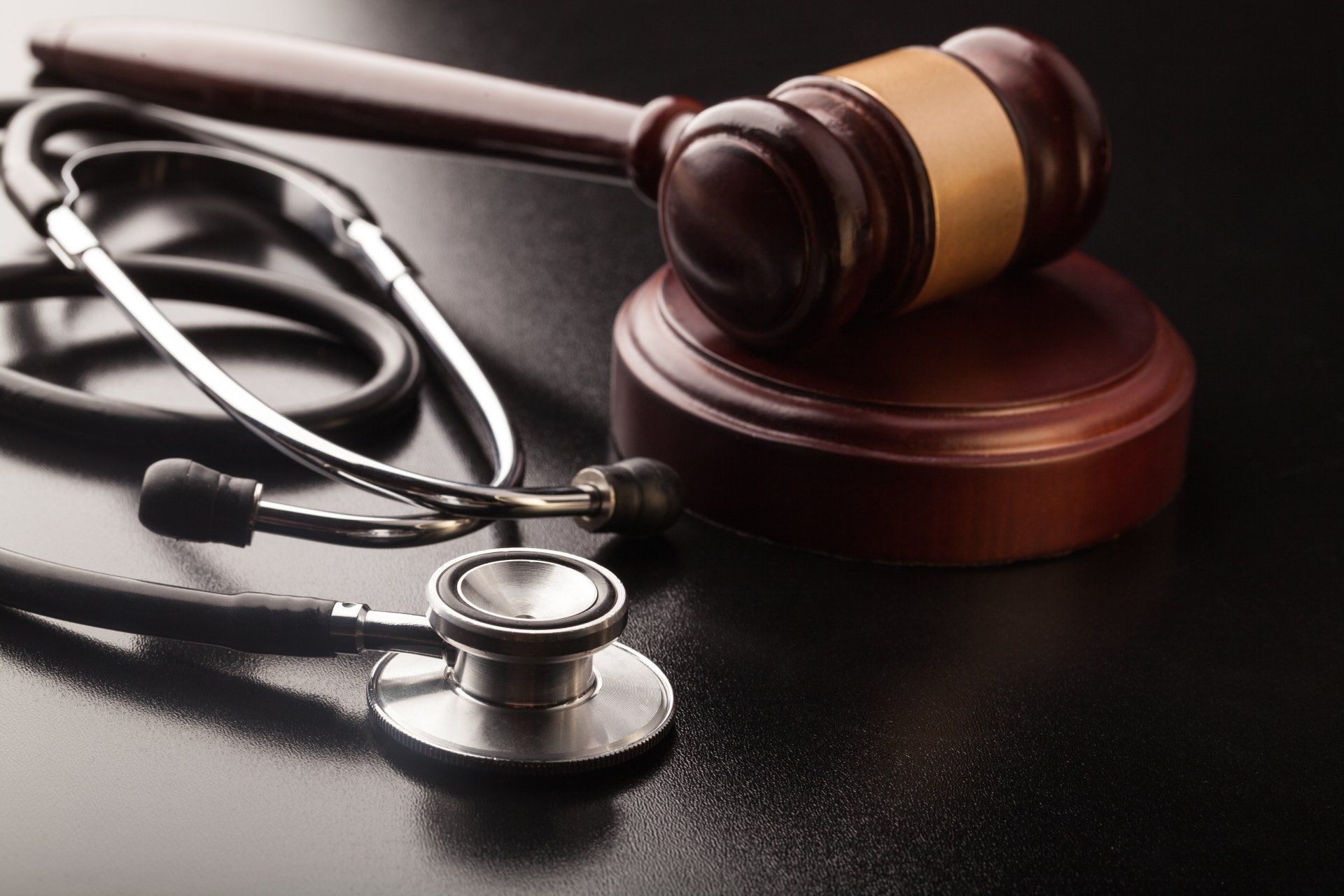 A stethoscope and a judge 's gavel are on a table.