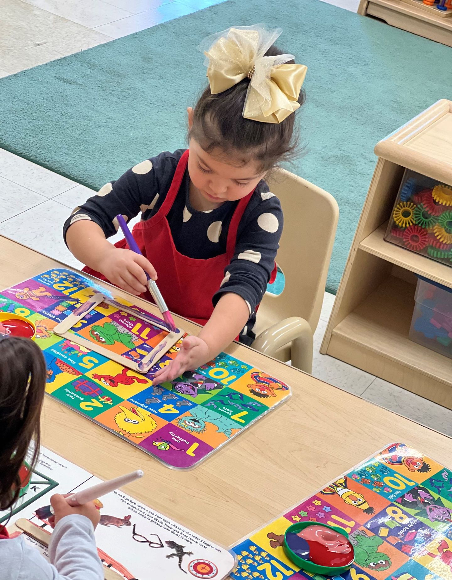 a little girl is sitting at a table playing with a puzzle .