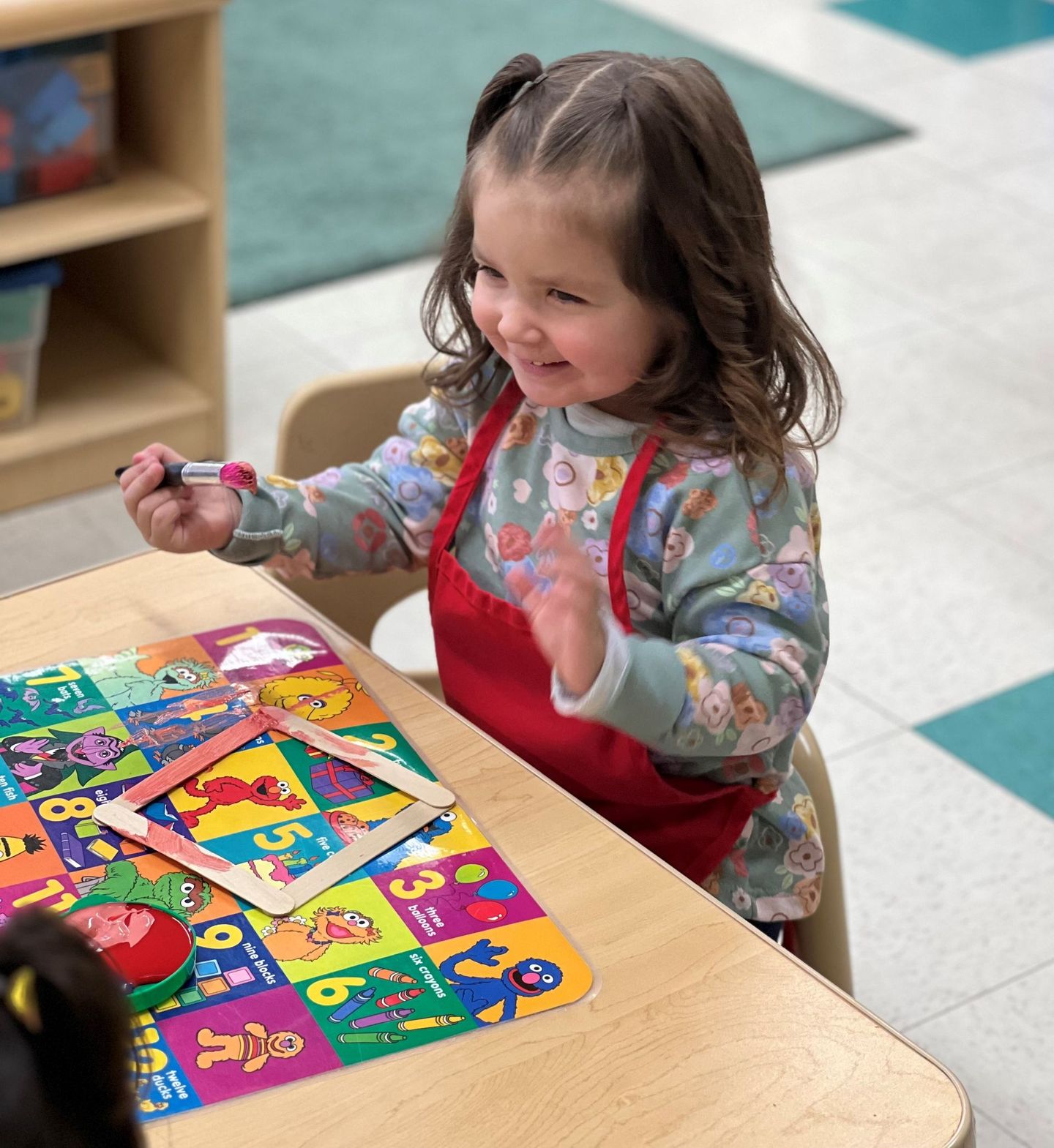 a little girl is sitting at a table playing with a puzzle .