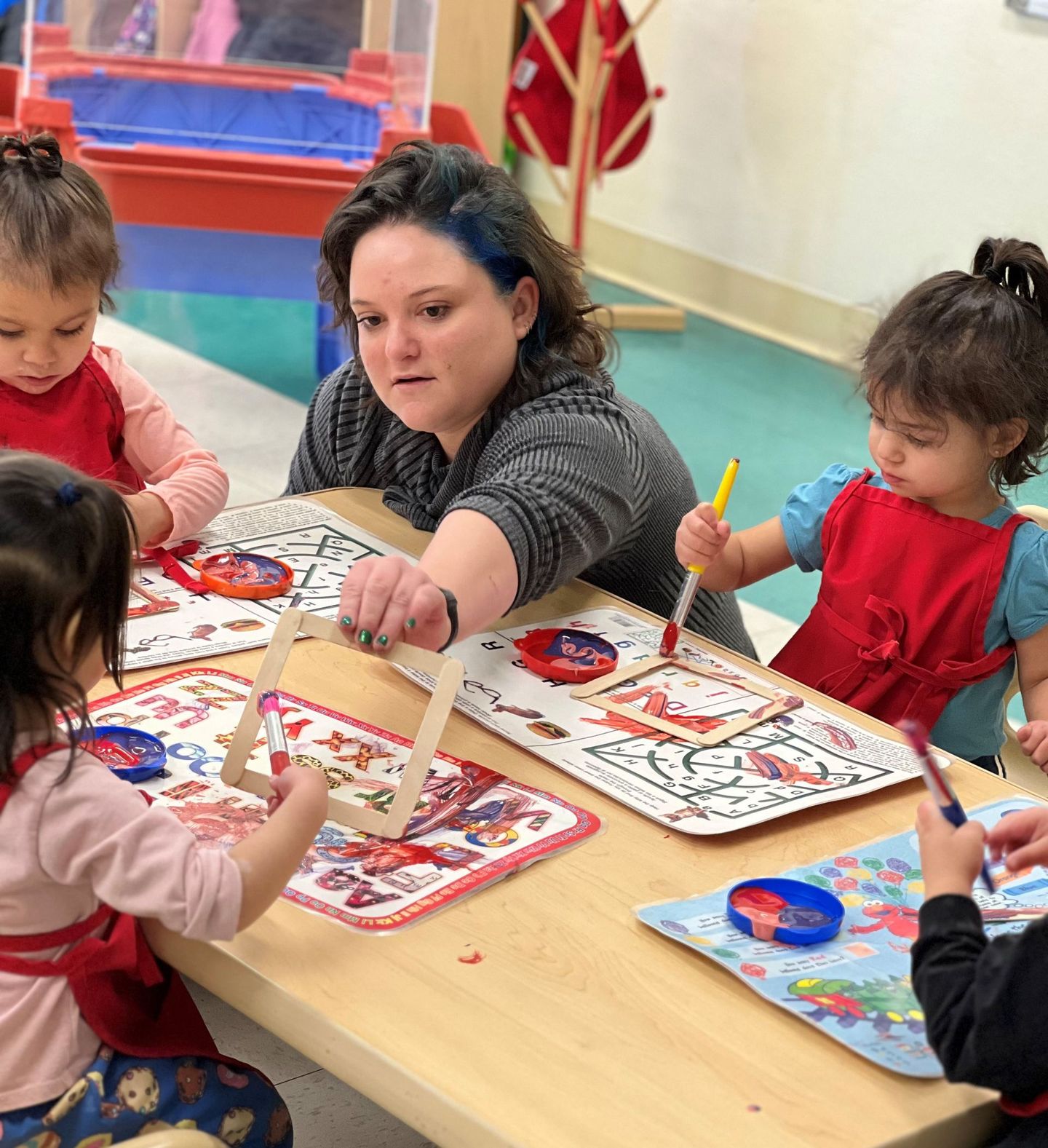 a woman and two little girls are sitting at a table painting .
