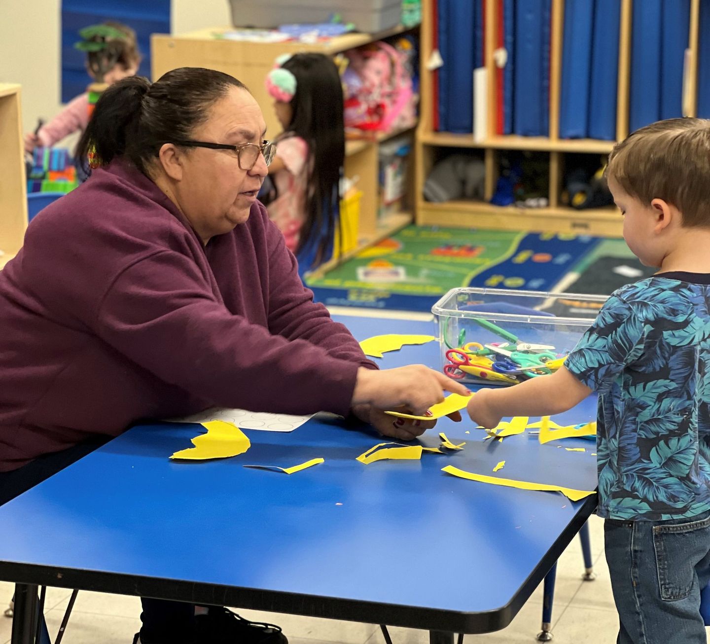 a woman is sitting at a table playing with a young boy .
