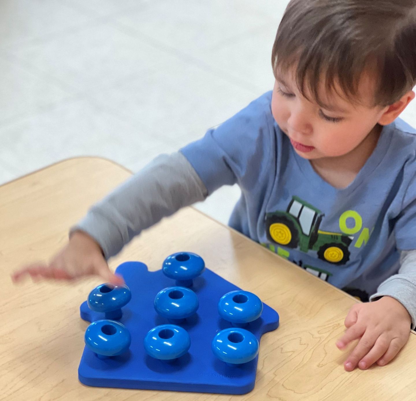 a young boy with a tractor on his shirt is playing with a toy
