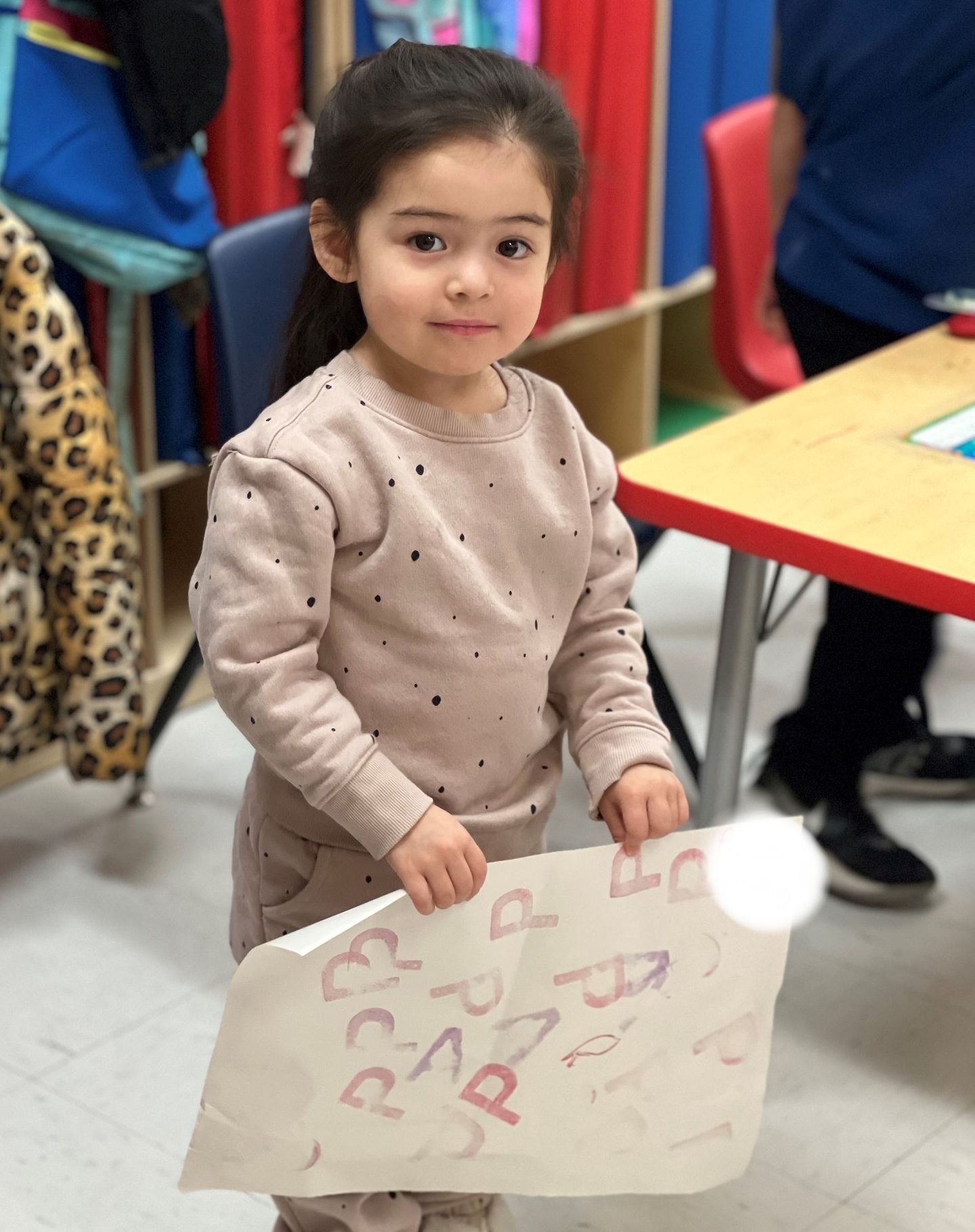 a little girl is holding a piece of paper with letters on it
