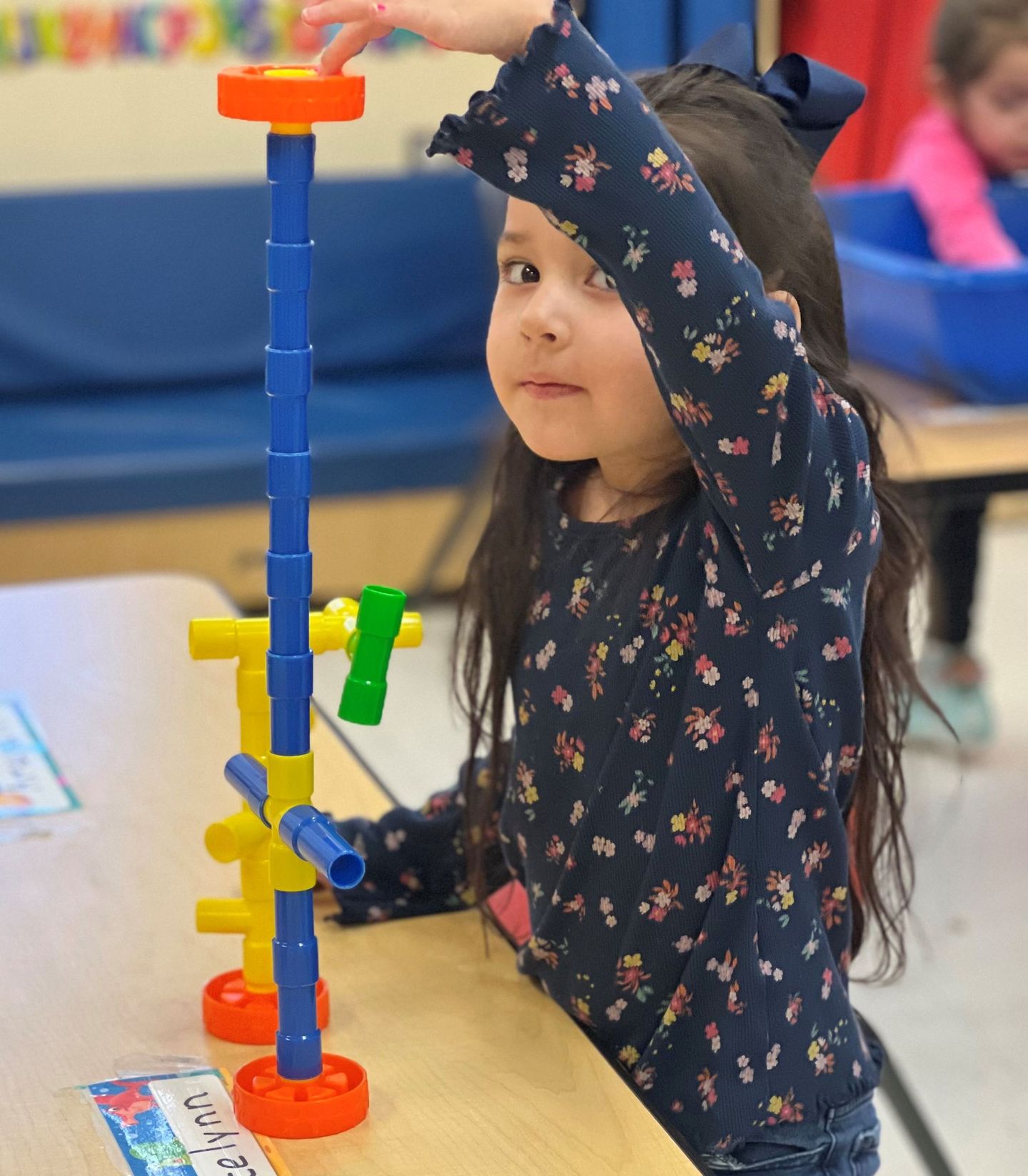 a little girl is playing with a marble run toy