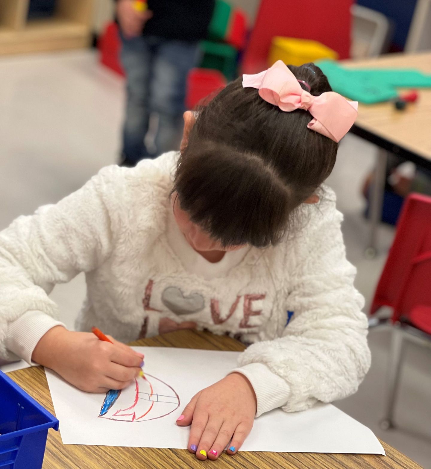 a little girl with a pink bow in her hair is drawing on a piece of paper