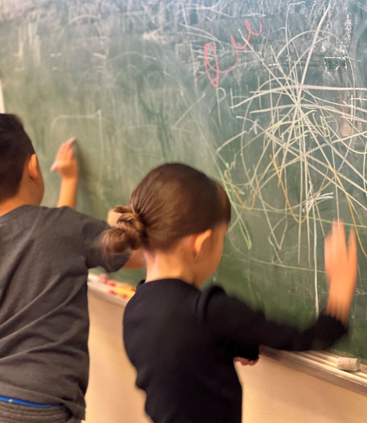 a boy and a girl are writing on a blackboard