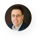 A man in a suit and glasses is smiling in a circle.