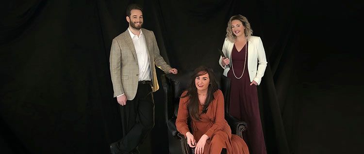 A group of people are posing for a picture in front of a black background.