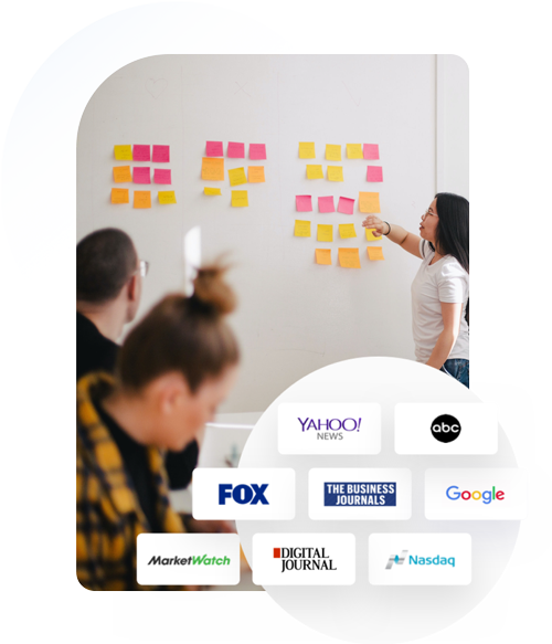 A group of people are sitting in front of a white board with sticky notes on it.