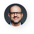 A bald man with glasses and a beard is smiling in a circle.
