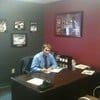 A man is sitting at a desk in an office talking on a cell phone.