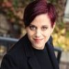 A woman with red hair is wearing a black jacket and a black shirt.