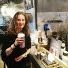 A woman is standing in a kitchen holding a cup of coffee.