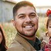 A man is smiling while holding a little girl.