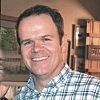 A man in a plaid shirt is smiling for the camera.