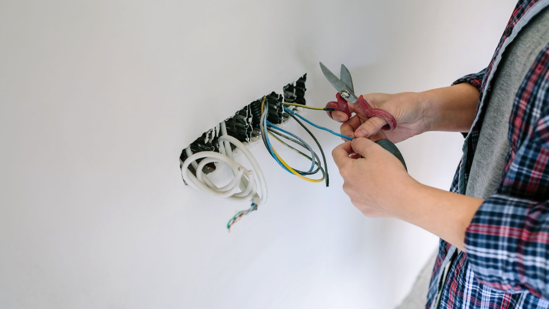 A person is cutting a wire with a pair of scissors.
