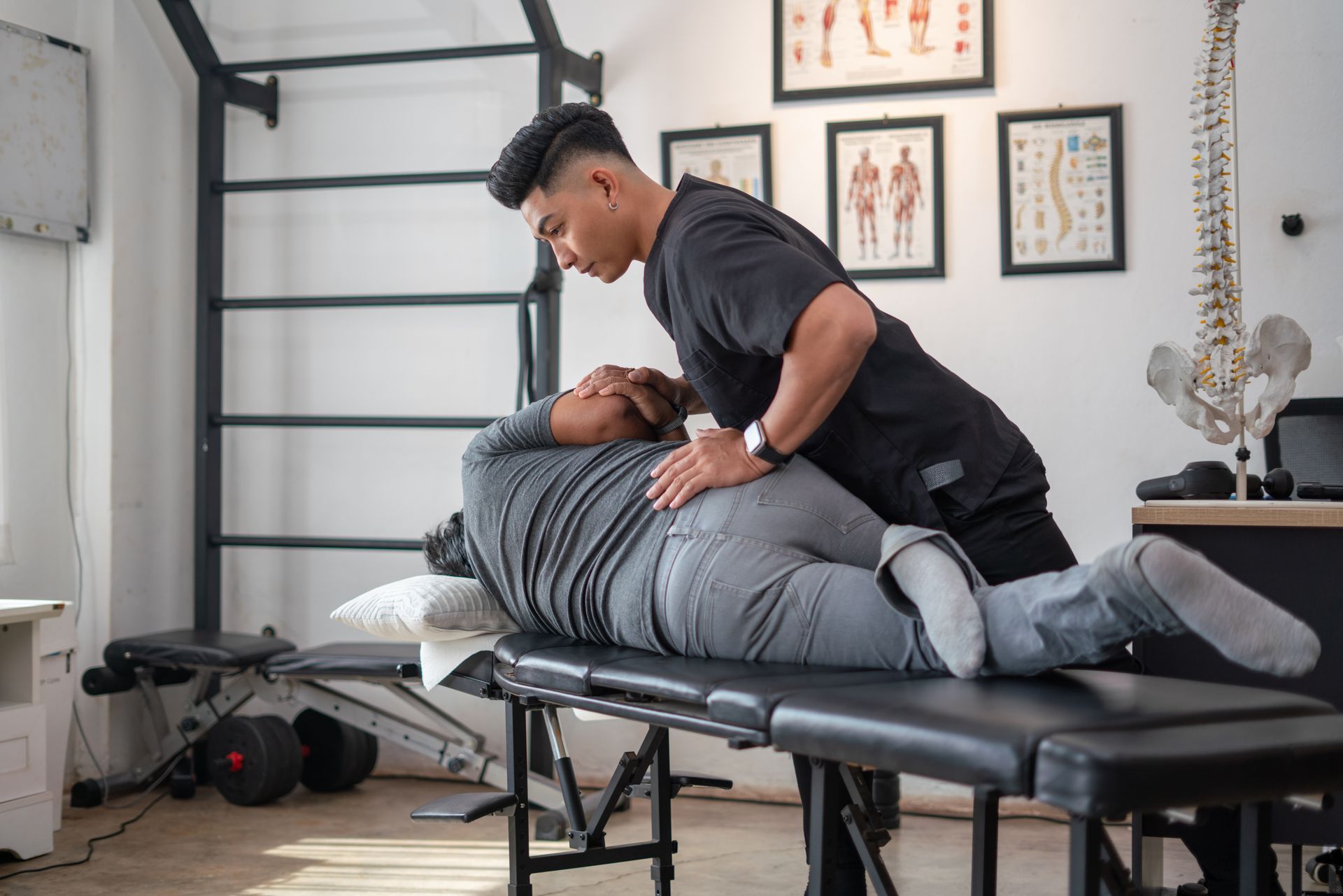 Chiropractor providing treatment to a patient lying face down on a massage table