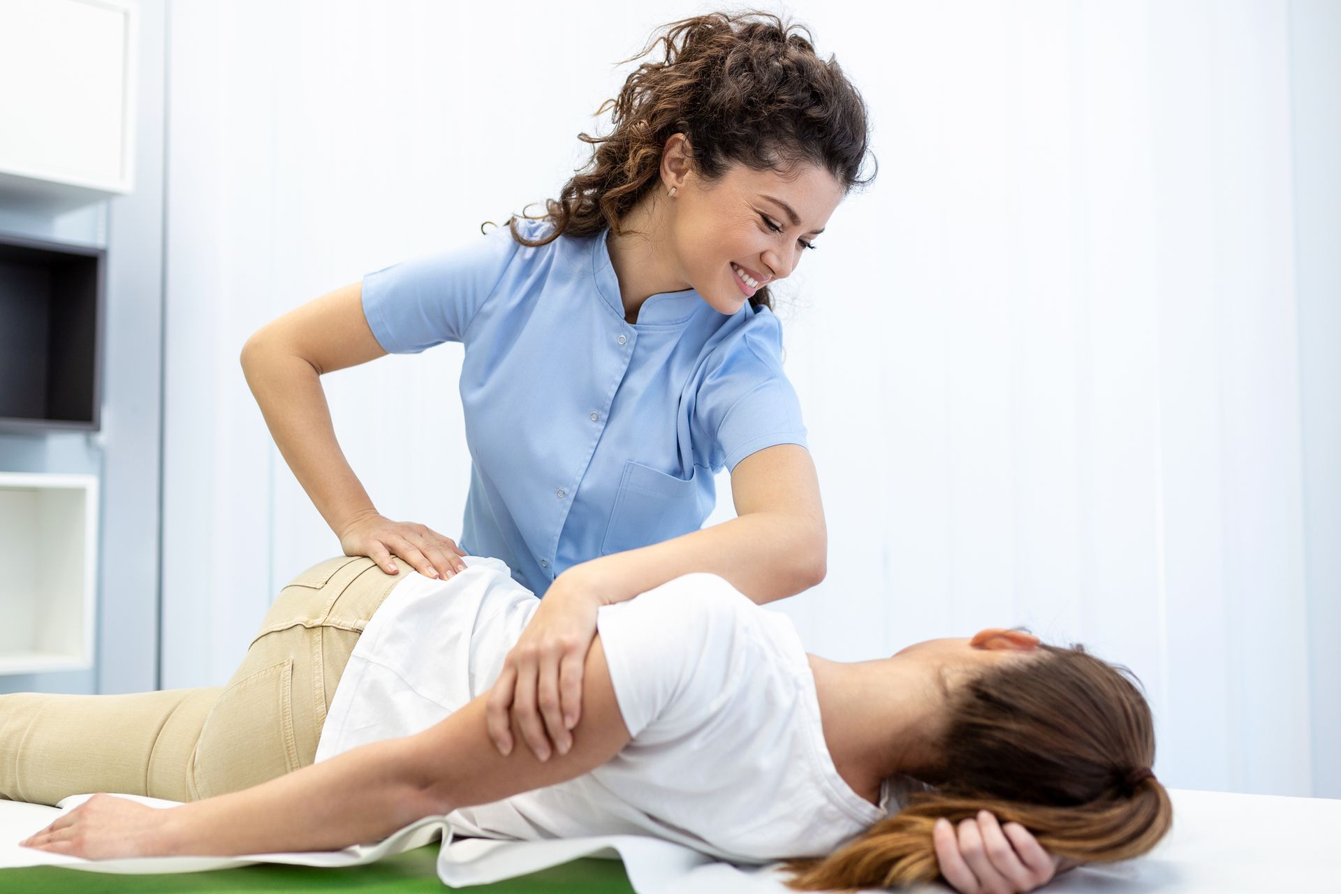 Physical therapist performing a side-lying spinal adjustment during a treatment session.