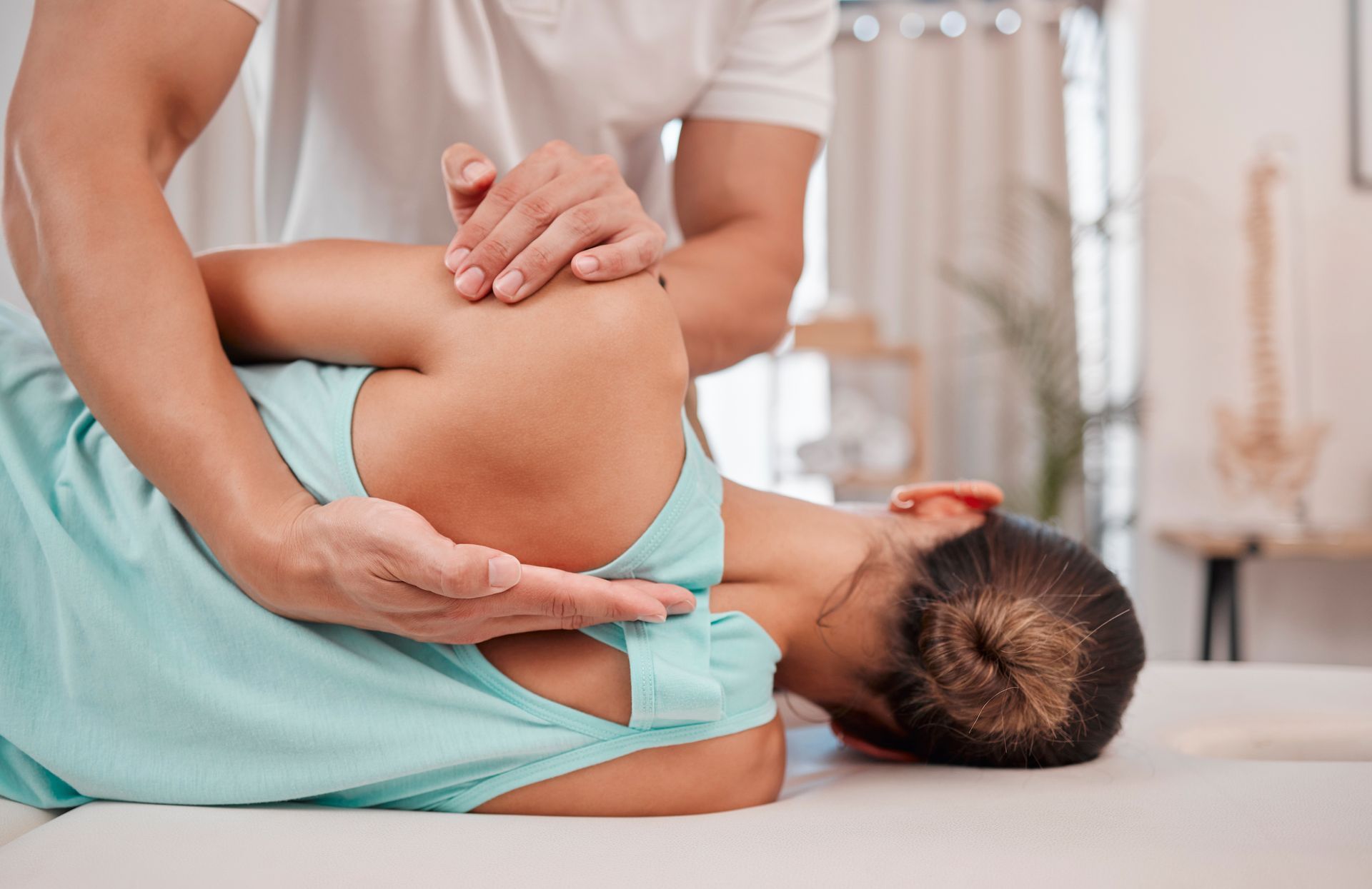 A chiropractor is healing a woman's spinal posture at a clinic.