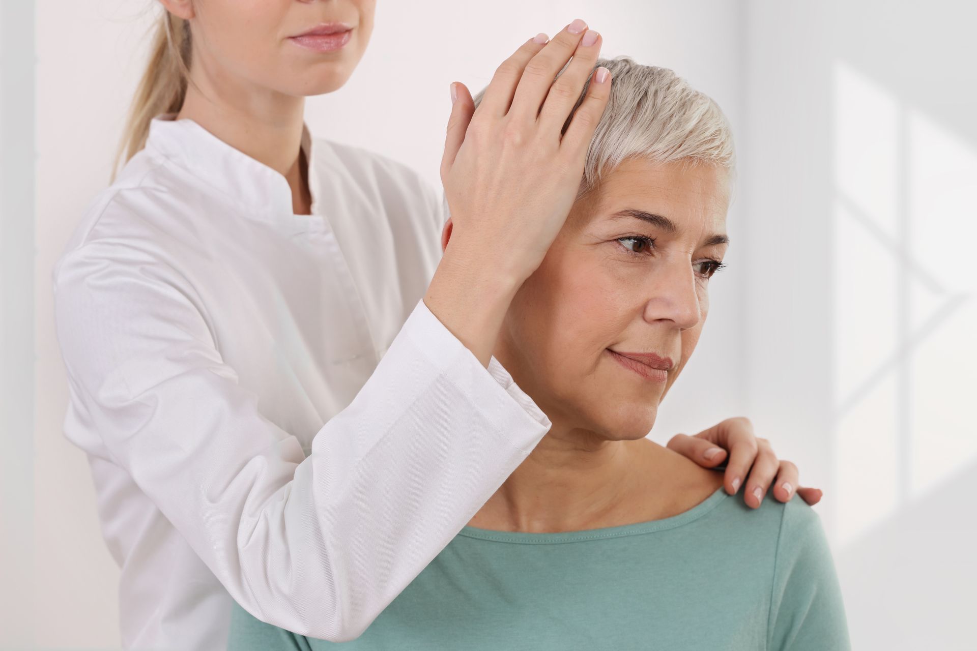 Healthcare professional examining scalp and short gray hair during dermatology checkup clinic visits.