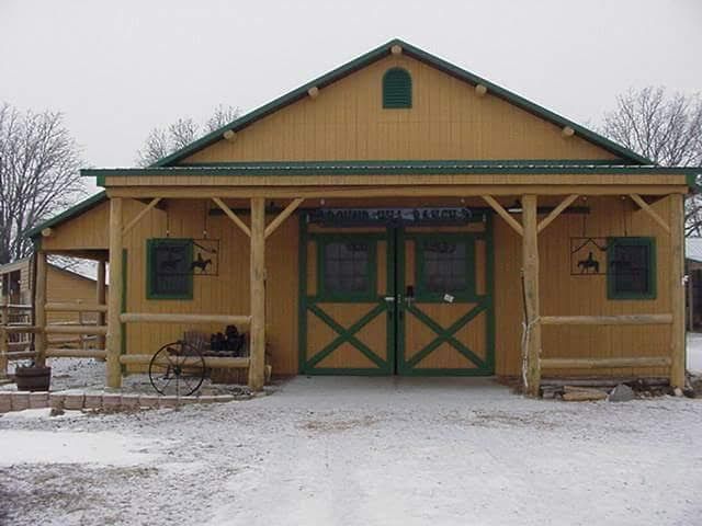 Wooden barn with green trim and double doors in a snowy rural setting