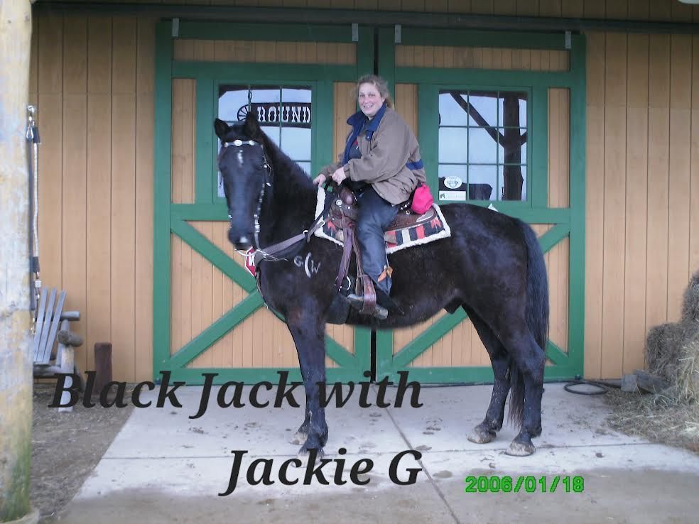 Woman on black horse in front of a stable, with “Black Jack with Jackie G” text overlay.