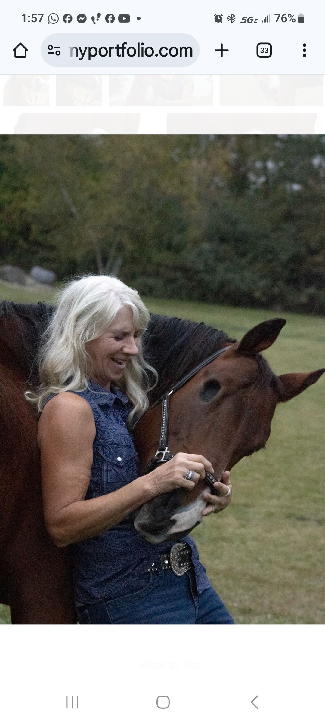 Woman in a blue dress smiling and petting a brown horse outdoors.