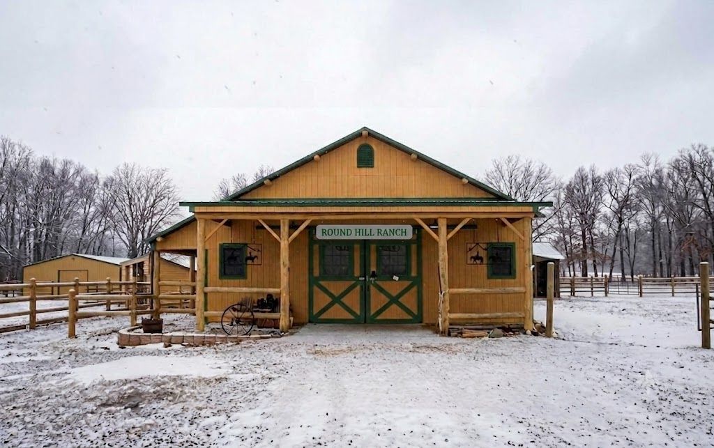 Wooden barn with green doors and snowy yard on an overcast winter day
