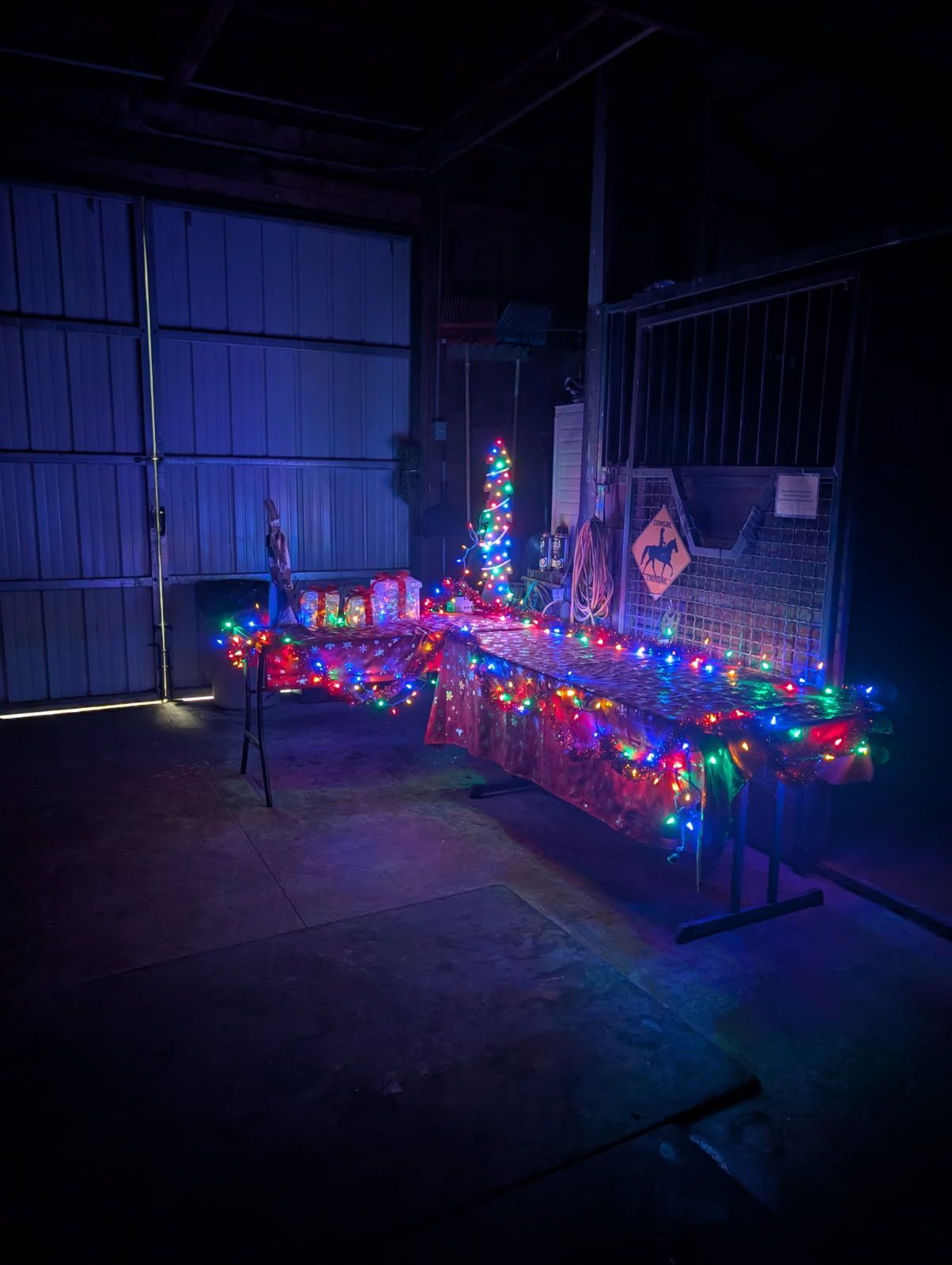 Dimly lit garage with colorful Christmas lights and glowing holiday decorations along a table.