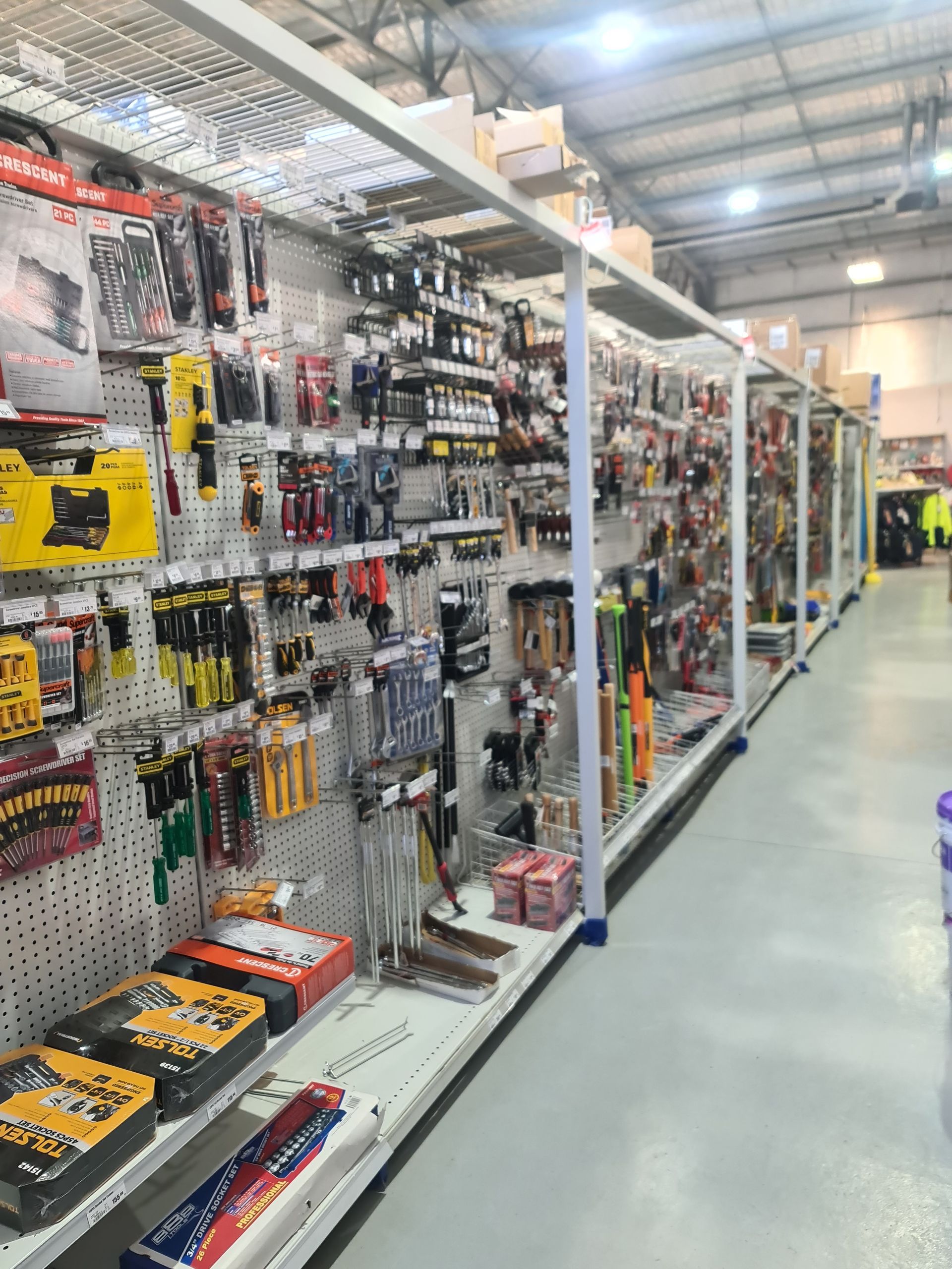A bunch of tools are hanging on a rack in a store.