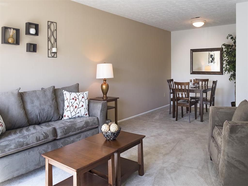 Living room with a gray sofa, coffee table, and a small dining area in an apartment at Shadow Hill, offering apartments in Sharonville, OH.