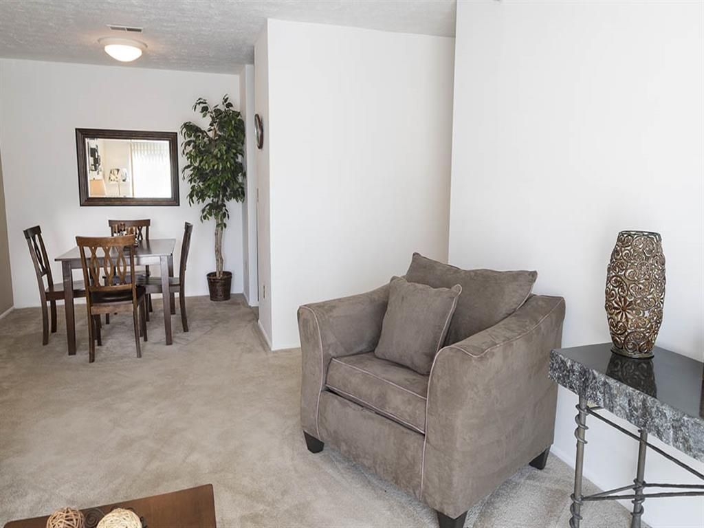 Living room and dining area in a neutral-toned apartment with a brown sofa and dining table at Shadow Hill, offering apartments for rent in Sharonville, OH.